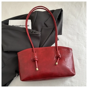 Detail of red faux leather tote bag with unique knotted strap and gold metal hardware