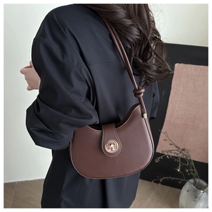 Detail of dark brown leather crescent bag with golden twist lock and knot strap