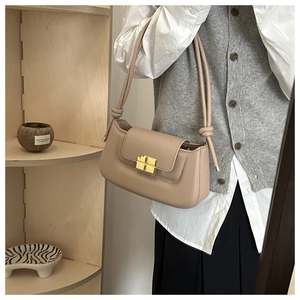 Detail of a beige baguette shoulder bag with a gold buckle and knotted strap accents