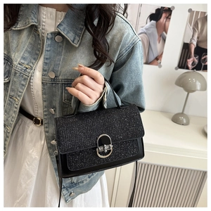 Detail of black sequined crossbody bag with silver oval metal twist lock clasp