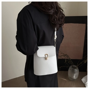 Sac seau blanc minimaliste avec fermoir doré élégant porté par un mannequin en vue