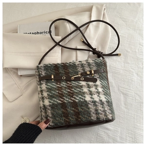 Close-up of retro plaid tweed bucket bag with dark brown leather and gold metal buckle