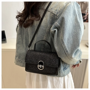 Close-up of black glitter crossbody bag featuring a silver oval metal turn-lock closure