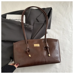 Detail of dark chocolate brown tote bag with gold metal plate and knotted strap
