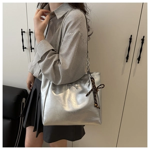 Silver metallic tote bag with bow detail and silk scarf on a model for casual look