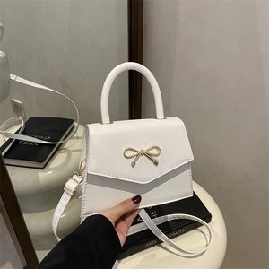Elegante weiße Trapez-Handtasche mit goldener Metallschleife und Schultergurt