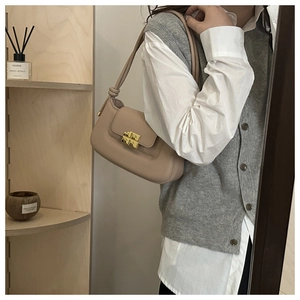Detail of beige shoulder bag with gold square buckle worn by model in casual style