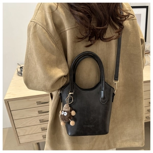 Detail of vintage black leather bucket bag with plush monster charm and logo