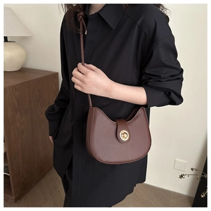 Gros plan d'un sac besace marron foncé avec un fermoir rotatif en métal doré rond