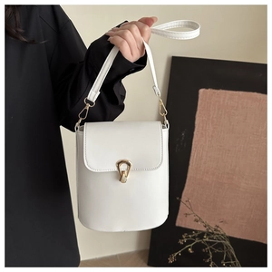Detailed view of white bucket bag with elegant golden shield buckle and leather texture