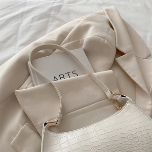 Minimalist white crocodile embossed crescent shoulder bag with golden zipper on beige suit