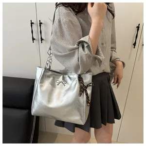 Close-up of silver tote bag with metallic bow detail and striped ribbon charm on the side