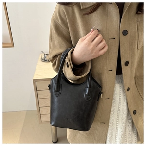 Detail of black matte bucket bag with embossed Fashion & Bags text and metal ring