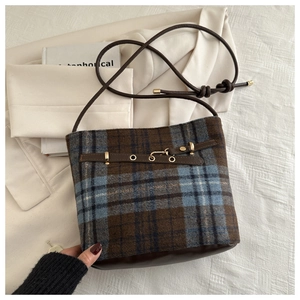 Detailed view of the checkered plaid bucket bag with brown leather trim and gold hardware