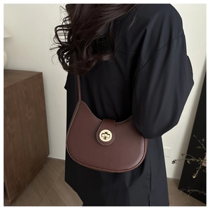 Dettaglio di una borsa hobo in pelle marrone con chiusura girevole dorata e design retrò minimal