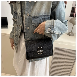 Detail of a chic black glitter handbag with round metal clasp and top handle style