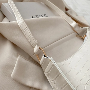 Minimalist beige crossbody bag with crocodile pattern and golden metal hardware detail