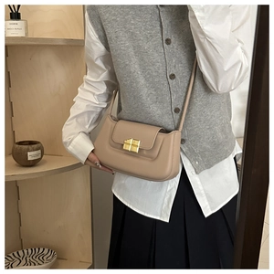 Detail of a beige leather baguette bag with a minimalist gold rectangular lock closure