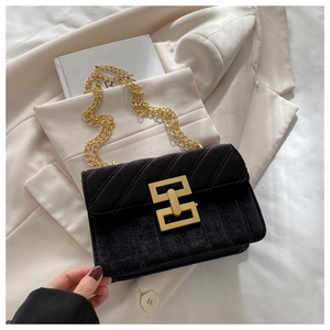 Close-up of black velvet chain bag with gold geometric lock and quilted texture
