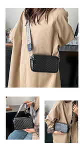 Détail du petit sac carré noir matelassé en V avec large bandoulière géométrique