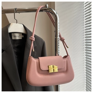 Close-up of pink crossbody bag with gold chocolate-shaped lock and knotted strap detail