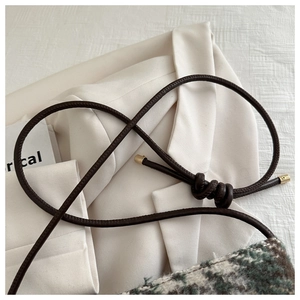 Detailed close-up of brown rope shoulder strap with gold tips and plaid tweed texture