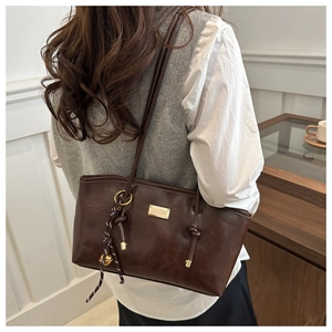 Detailed side view of a vintage dark brown leather tote bag with a decorative woven strap