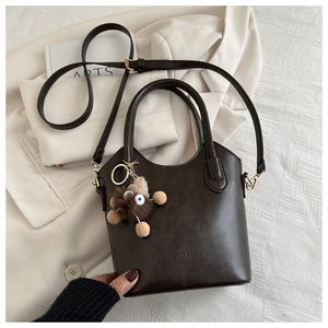 Detail of vintage brown bucket bag with plush charm and fashion text embossing