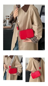 Détail d'un sac bandoulière rouge matelassé avec une large sangle tissée aux motifs géométriques