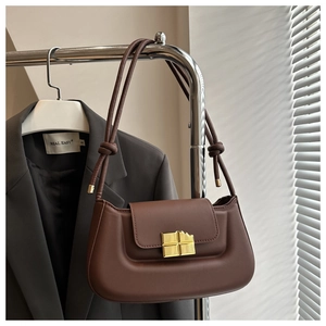 Detail view of a brown faux leather shoulder bag featuring a unique gold chocolate bar clasp