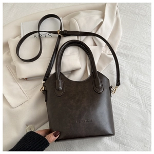 Detailed view of the dark brown bucket bag featuring embossed logo and gold hardware