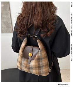 Close-up of brown plaid backpack showing leather flap and golden N-engraved buckle