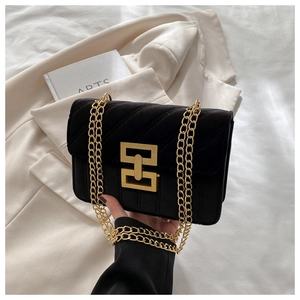 Close-up of black velvet crossbody bag with V-shaped quilting and gold chain strap