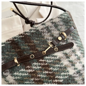 Detail of green tweed crossbody bag showing textured fabric and gold metal rings