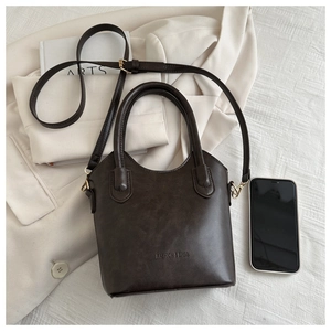 Top view of brown vintage bucket bag with Fashion & Bags logo next to a smartphone