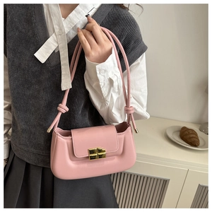 Pink minimalist baguette bag with golden buckle and knotted strap detail worn by model