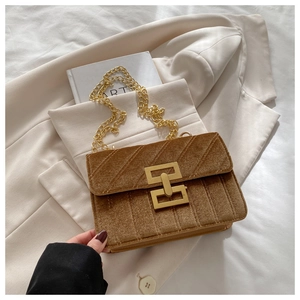 Detail of brown quilted suede crossbody bag with gold metal clasp and chain strap