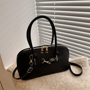 Close-up of black leather bowling bag with gold hardware and dual zippers on cream rug