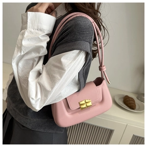 Pink leather baguette bag detail with gold metal buckle and decorative knotted shoulder strap