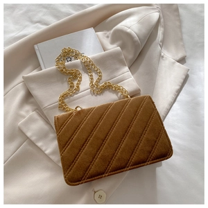 Detail of a brown velvet crossbody bag featuring diagonal quilting and a gold metal chain strap