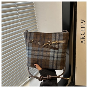 Detail of vintage plaid bucket bag featuring blue brown check fabric and leather strap
