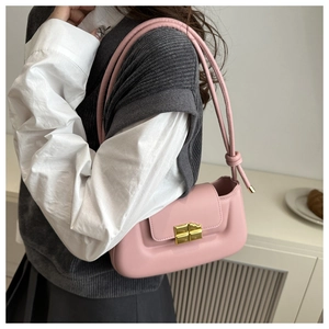 Detail of a pink leather shoulder bag with a gold metal clasp and knot strap