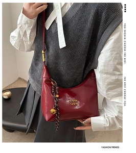 Close-up of vintage dark red leather bag with golden logo and bell charm detail