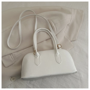 Detail of white bowling handbag with gold zipper on cream fabric and blazer