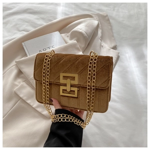 Detail of dark brown velvet crossbody bag with golden geometric buckle and chain strap