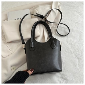 Detail view of black matte leather bucket bag with embossed logo and adjustable strap