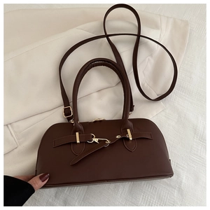 Detail of dark brown matte leather handbag with gold hardware on white textured background