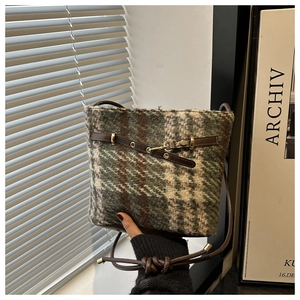 Detail of vintage plaid wool bucket bag with leather strap and gold hardware accents