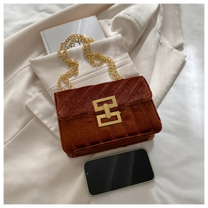 Close-up of brown quilted velvet crossbody bag with gold chain strap and smartphone for scale