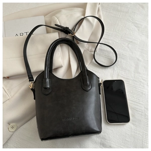 Detail view of black matte bucket bag with top handles and adjustable slim shoulder strap